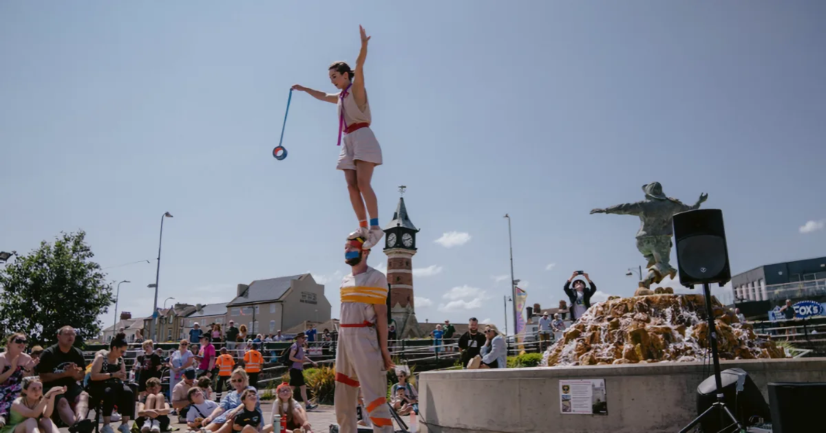 Colourful outdoor performance at a coastal arts festival on a bright summer afternoon